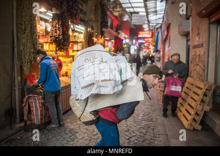 Un maschio adulto porta diverse borse pesanti di merci per il suo ritorno al mercato all'aperto, Istanbul, Turchia Foto Stock