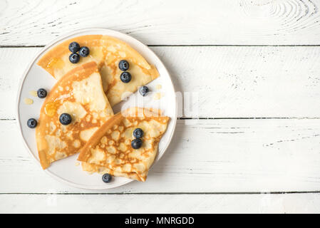 Crepes con mirtilli e miele. Frittelle fatte in casa, crepes sul tavolo bianco, copia dello spazio. Foto Stock