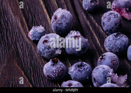 I mirtilli bacche close-up di un gelo con ghiaccio su una tavola di legno superficie scura Foto Stock