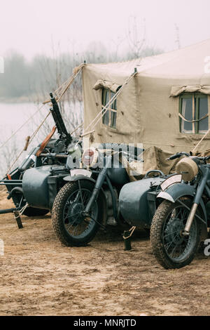 Antico tedesco di motocicli di colore grigio dai tempi della Seconda Guerra mondiale con una mitragliatrice montata sulla culla sono situati presso la tenda militare Foto Stock