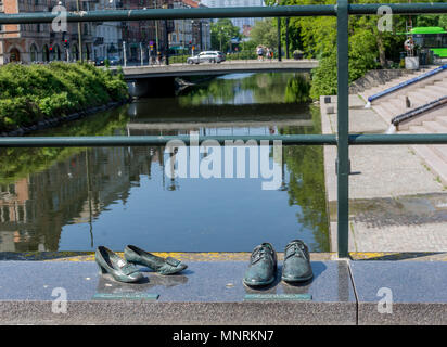 Sculture in bronzo di moda e abbigliamento scarpe sul curtsied con il fiume e il ponte in background. Foto Stock