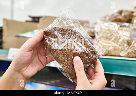 Mani con semi di lino per i prodotti alimentari in negozio Foto Stock