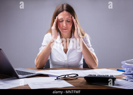 Imprenditrice che soffrono di mal di testa seduto in ufficio Foto Stock