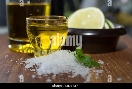 Cucina ancora in vita con sale marino, coriandolo, l'olio di oliva nel colpo di vetro e fettine di lime in piccolo marrone scuro recipiente di ceramica su tavola in legno di quercia