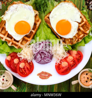 La prima colazione tradizionale. Uova fritte e pomodori su una piastra bianca. Spolverati con formaggio grattugiato. Square. Close-up. Foto Stock