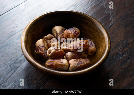 Data secca frutti di palma o kurma, ramadan ( ramazan ) Medjool cibo nella ciotola di legno. Frutta organica. Foto Stock