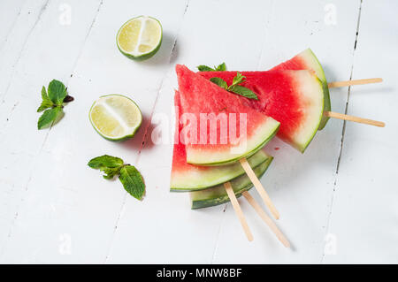 Fetta di cocomero e popsicles lime sul legno rustico sfondo. Foto Stock