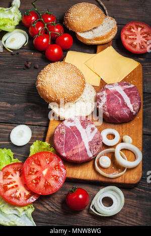 Ingredienti per fare in casa burger sul tagliere di legno. Foto Stock