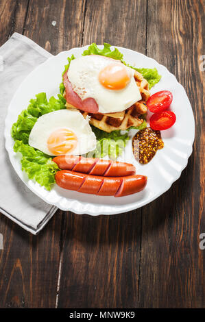 I waffle belgi con uova e salsiccia sulla tavola di legno. Foto Stock