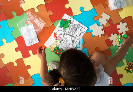 Bambino ragazza che gioca con il puzzle puzzle tappeto. Scatto dall'alto. Rumore morbido al 100% Foto Stock