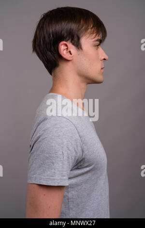 Giovane uomo bello pronto per palestra contro uno sfondo grigio Foto Stock