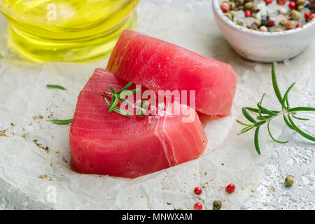 Tonno crudo tranci di pesce con sale marino e pepe e rosmarino per grill o cottura. Preparare una cena deliziosa. Messa a fuoco selettiva Foto Stock