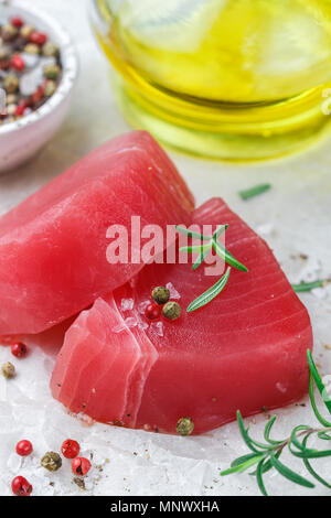 Tonno crudo tranci di pesce con sale marino e pepe e rosmarino per grill o cottura. Preparare una cena deliziosa. Messa a fuoco selettiva Foto Stock