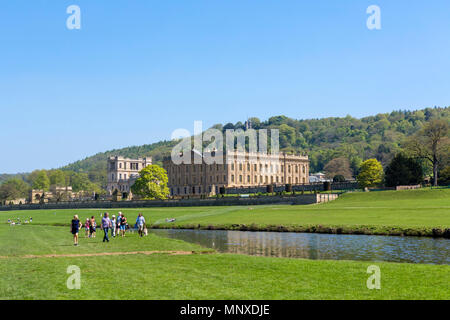 I visitatori a piedi lungo il Fiume Derwent in Chatsworth Park con Chatsworth House dietro, Chatsworth, Derbyshire, England, Regno Unito Foto Stock