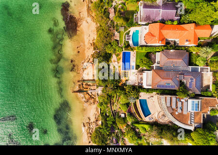 Ricchi case residenziali sulla centrale di Sydney Harbour waterfront toccando pulite remota spiaggia sabbiosa in aerial vista aerea su una soleggiata giornata splendente. Foto Stock