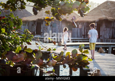 I ragazzi del fratello e sorella camminando sulla passerella di legno durante le vacanze estive a resort di lusso Foto Stock