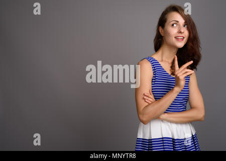 Giovane bella donna contro uno sfondo grigio Foto Stock