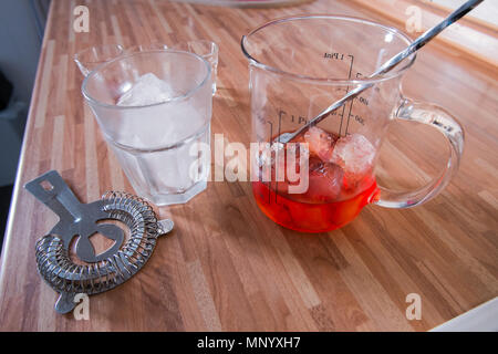 La miscelazione di un negroni cocktail sulla cucina in legno piano di lavoro Foto Stock