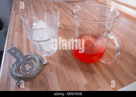 La miscelazione di un negroni cocktail sulla cucina in legno piano di lavoro Foto Stock
