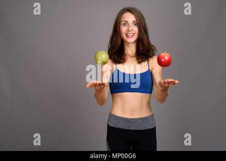 Giovane bella donna pronta per la palestra contro uno sfondo grigio Foto Stock