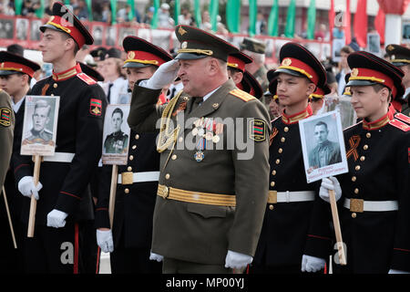 Un ufficiale con i cadetti delle Forze Armate della Pridnestrovian Repubblica Moldava del semi-riconosciuta dallo stato della Transnistria azienda foto di coloro che hanno combattuto nella guerra mondiale II durante una cerimonia militare in occasione della Giornata della vittoria il 9 di maggio che commemora la vittoria dell'Unione Sovietica sulla Germania nazista nel centro di Tiraspol la capitale e il centro amministrativo dei confini internazionalmente riconosciuti della Moldavia sotto il controllo de facto della riconosciuta Pridnestrovian Repubblica Moldava anche chiamato Transnistria (PMR) dal 1992. Foto Stock