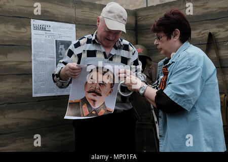 I civili hanno in mano un poster con la foto di Stalin mentre hanno allestito uno stand commemorativo durante il giorno della Vittoria il 9 maggio, una festa che commemora la vittoria dell'Unione Sovietica sulla Germania nazista nel 1945 nella città di Bender de facto nome ufficiale Bendery all'interno del mondo confini riconosciuti della Moldavia sotto il controllo de facto della Repubblica moldava di Pridnestrovia, chiamata anche Transnistria (PMR), non riconosciuta dal 1992. Foto Stock