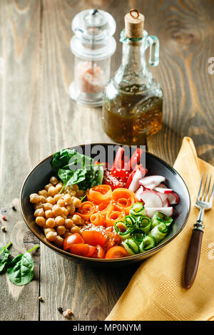 Buddha colorato ciotola con ceci, carote, pomodori, cetrioli, radicchio e peperoni su di un tavolo di legno. Insalata vegetariana. Foto Stock