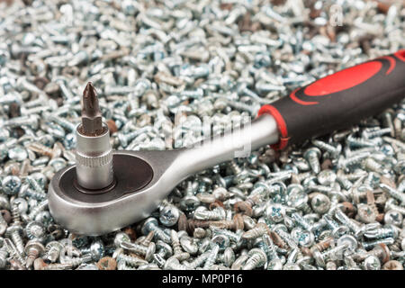 Cacciavite giacente su un mucchio di viti. Close-up Foto Stock