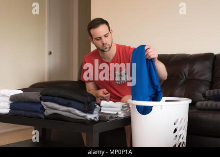 Uomo bello lavanderia di piegatura su un divano Foto Stock