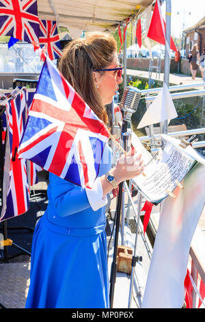 Saluto alla 40s popolare nostalgico. Donna Midadult cantante dalla vittoria di banda di guerra, sventolando Unione Jack e il canto sul ponte di P22 a sandwich. Foto Stock