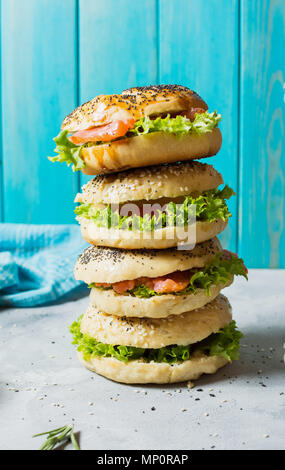 Bagel con salmone, verdure, crema di formaggio e un bicchiere di vino rosso sul cemento grigio Sfondo. Foto Stock