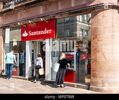 Un cliente entra in una filiale della banca di Santander mentre due altri utilizzano gli sportelli bancomat all'esterno. Hamilton, South Lanarkshire, Scotland, Regno Unito Foto Stock