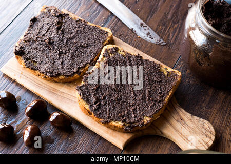 Nero oliva Tapenade su pane con coltello e Jar. Alimenti biologici. Foto Stock