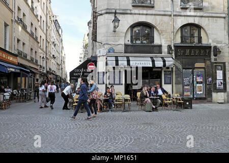 Coppia a piedi da persone sedute ai tavoli fuori le Paradis all'angolo di Rue de la Verrerie & Rue Saint-Martin Parigi Francia Europa UE KATHY DEWITT Foto Stock