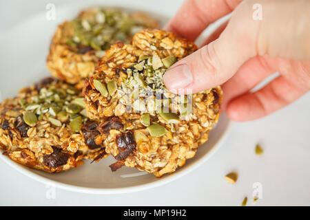 Vegano biscotti di farina di avena con le date e i semi di zucca sulla piastra bianca. Sano cibo vegan concetto. Foto Stock