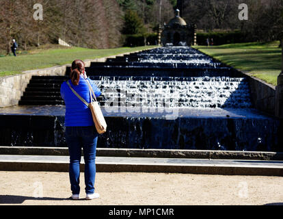 Una signora turistica prendendo una foto della cascata nel parco di Chatsworth House vicino a Bakewell nel Derbyshire Foto Stock