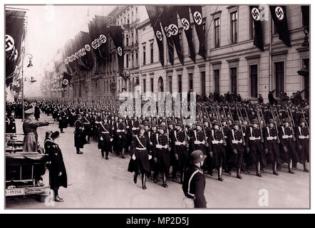 Adolf Hitler nella sua parte superiore aperta autovettura Mercedes saluta una parata della sua guardia del corpo personale reggimento il 1° Divisione SS Leibstandarte Waffen SS con edifici adornato con bandiere con la svastica gennaio 30th, 1937 Foto Stock