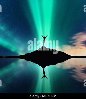 Aurora e silhouette di donna con sollevata bracci sulla montagna. Paesaggio notturno con aurora boreale, felice girl, stelle polari verde luci, lak Foto Stock