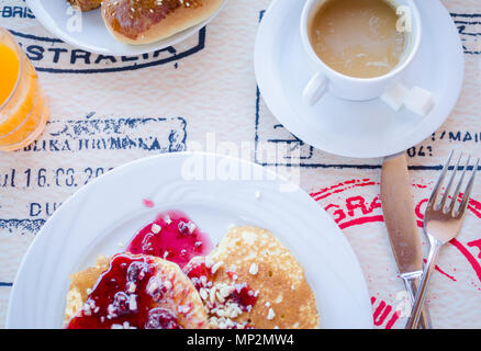 Prima colazione inclusa classic pancake con confettura di lamponi, caffè con latte e prodotti di pasticceria. Buona mattina. Vista dall'alto. Foto Stock