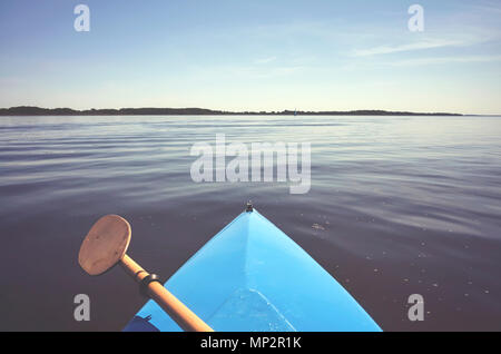 Prua di un kayak con paddle su ancora un lago, dai toni di colore foto, messa a fuoco selettiva. Foto Stock