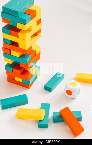 Blocchi colorati e una torre di Jenga gioco su uno sfondo bianco con i dadi Foto Stock