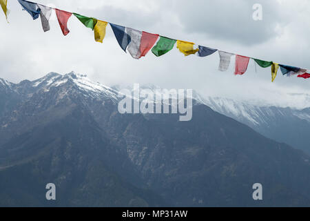 Colorati bandiere di preghiera e delle montagne innevate, visto durante le escursioni su Bumdra trek vicino a paro, Bhutan Foto Stock