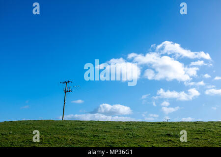 Le linee di alimentazione in terreni agricoli con profondo cielo blu e soffici nuvole nel Cheshire Regno Unito Foto Stock