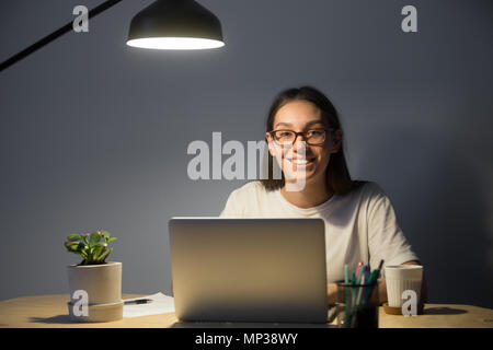 Felice freelancer sorridente alla telecamera che pongono alla scrivania in ufficio Foto Stock