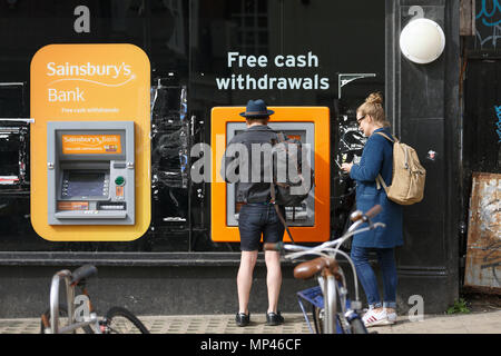 Un uomo di ritirare denaro contante in un Sainsbury's ATM. Foto Stock