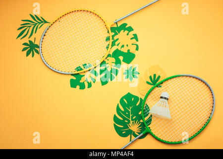 La vacanza estiva piatto con laici badminton beach set e foglie tropicali. Testata sportiva su un brillante sfondo giallo con copia spazio. Foto Stock