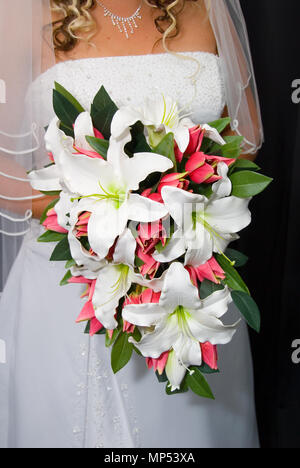 Sposa che tiene un bouquet nuziale di gigli bianchi e tulipani rosa. Foto Stock
