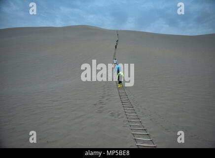 Salendo ventoso dune di sabbia, Mingsha Shan (cantando Sands montagna), Dunhuang, Gansu, Cina Foto Stock