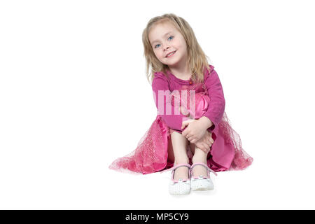 Ritratto di bambina seduta sul pavimento, abbracciando le ginocchia, isolato su sfondo bianco Foto Stock