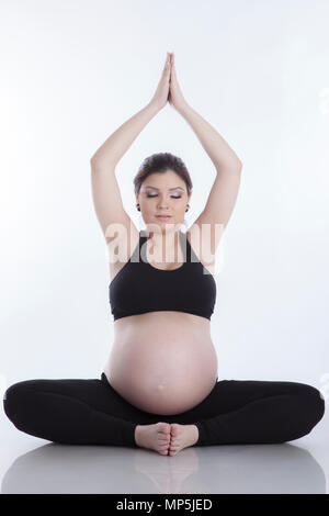 Donna incinta rilassarsi facendo yoga, seduti nella posizione del loto su sfondo bianco Foto Stock